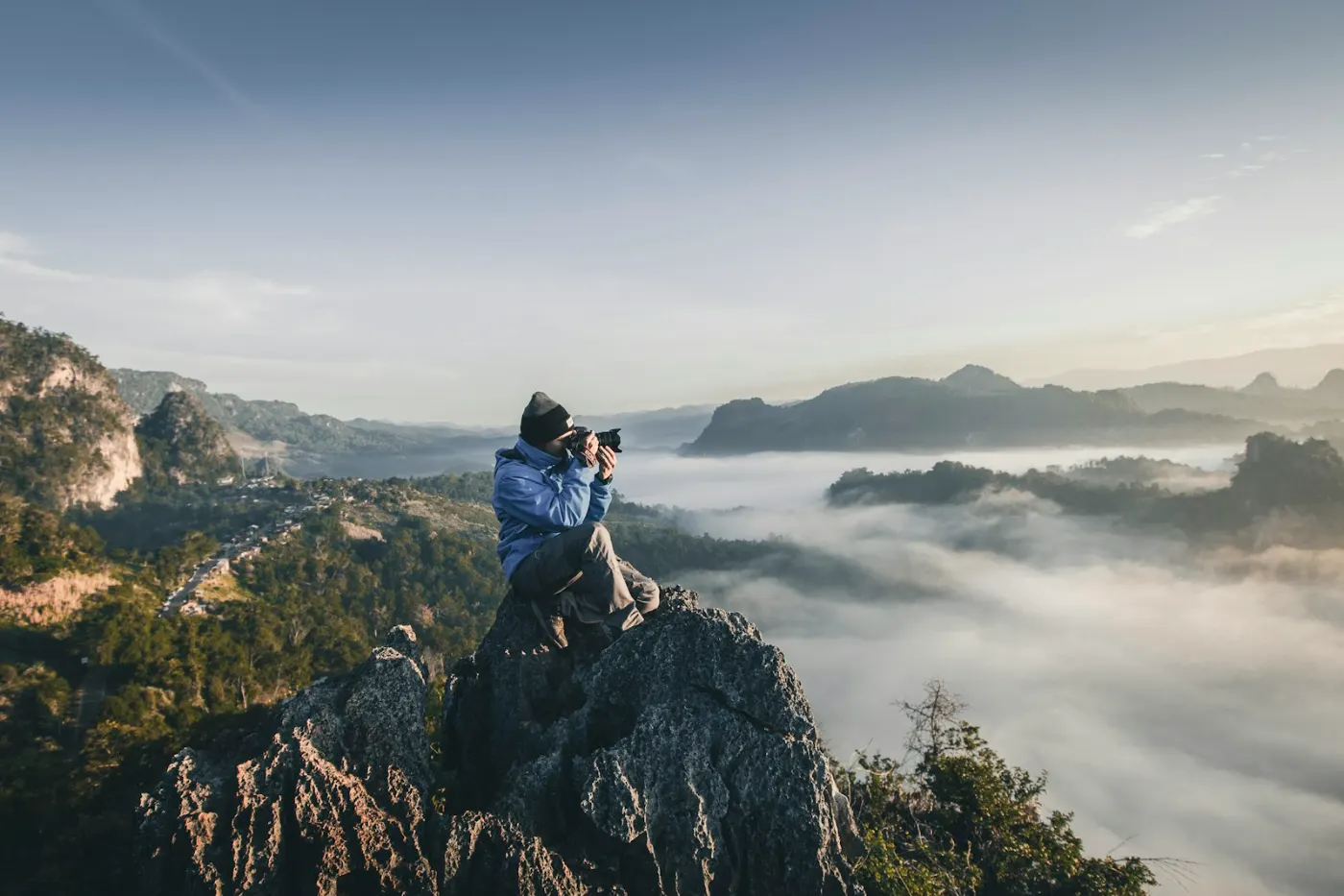 Fotograf auf einem Felsen über einem Wolkenmeer